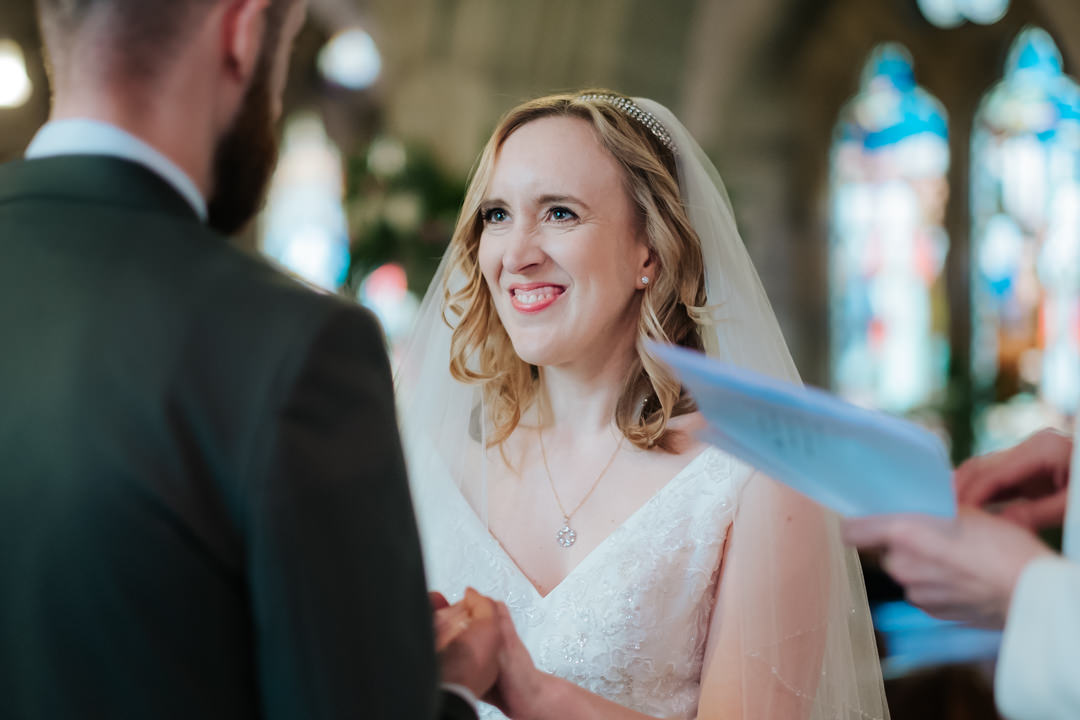 Bride looking into the Groom's eyes and smiling on their wedding day at Old Milverton Church