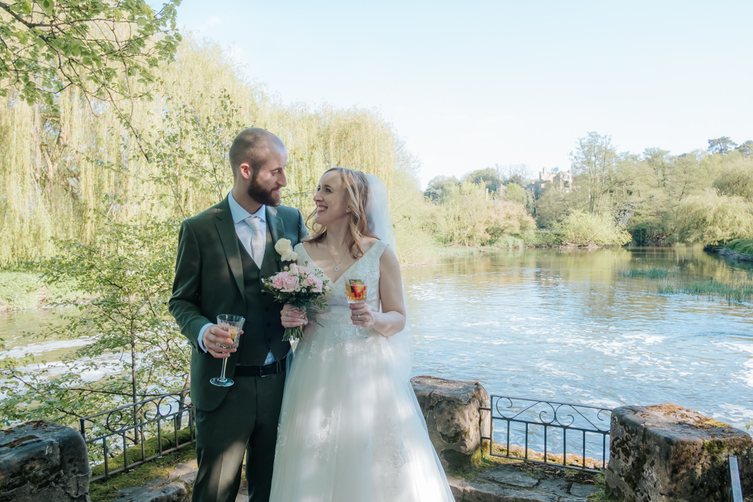 Saxon Mill wedding. bride and groom standing on the riverside with pimms
