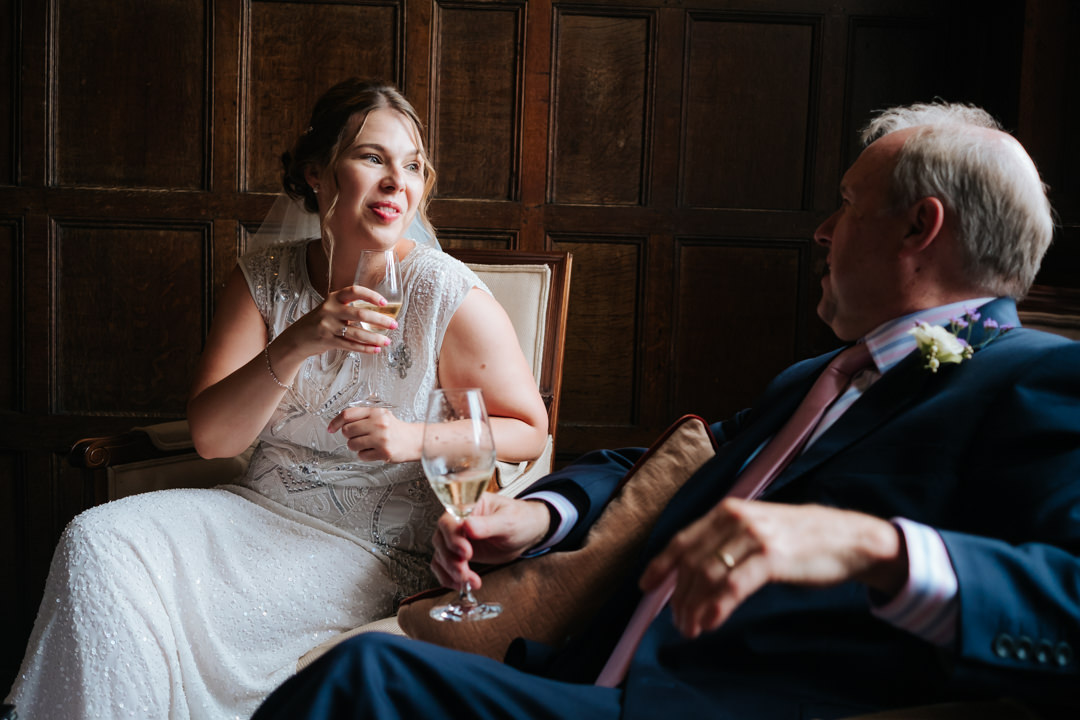 bride and her father enjoy a glass of champagne before her wedding at Gravetye Manor