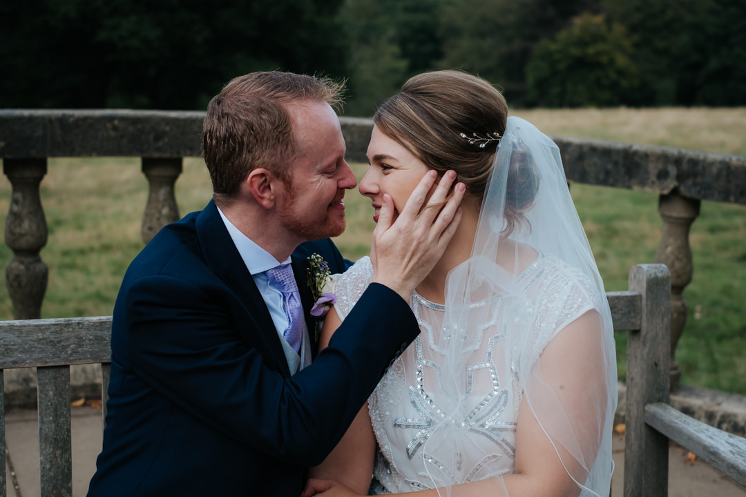 Bride and groom kiss in front of beautiful views after their wedding at Nymans Gardens