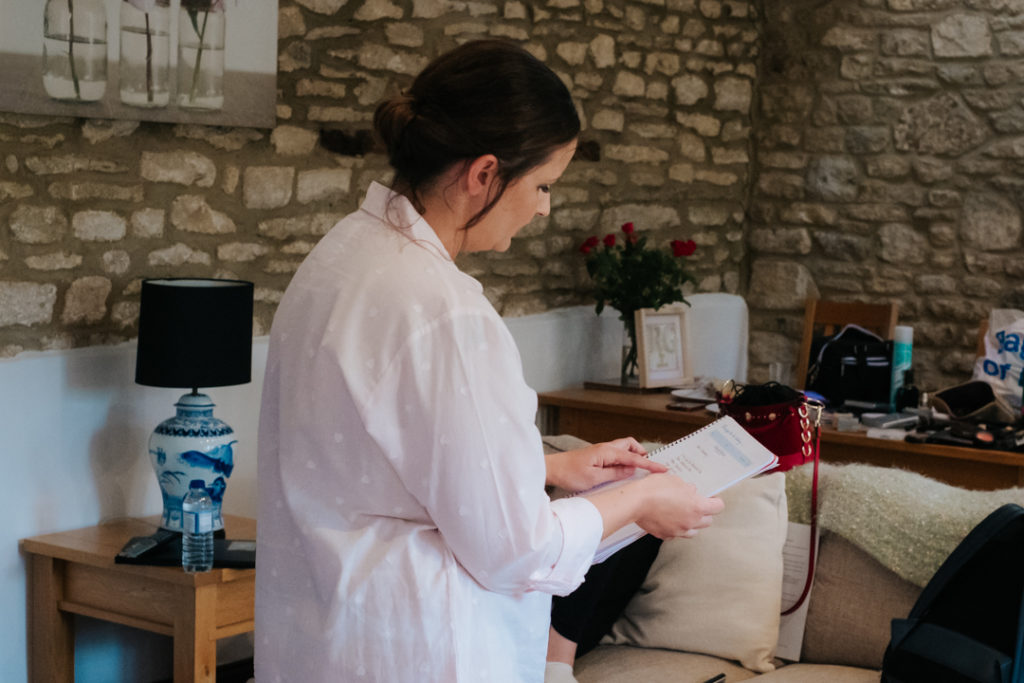 bride reading her checklist as she gets ready at Worton Hall on the morning of her wedding