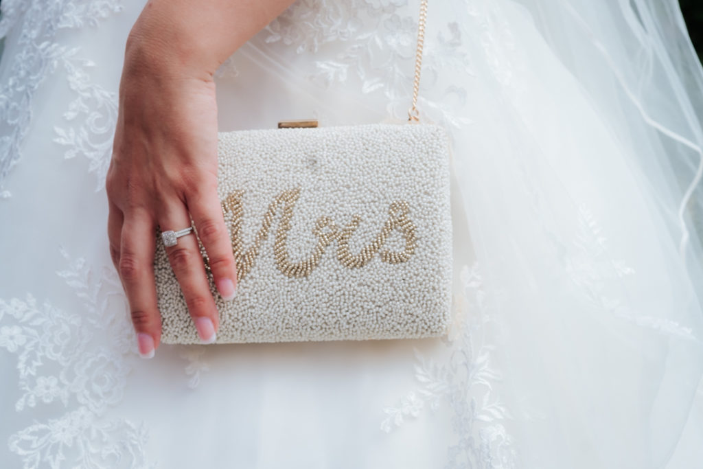 brides hand holding her handbag which spells "MRS" in gold jewels at her Worton Hall wedding
