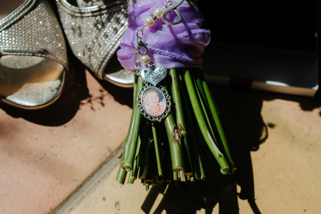 the stems of a wedding bouquet focussed in on a keepsake photograph of the bride's late grandma, with engraved heart reading special nan