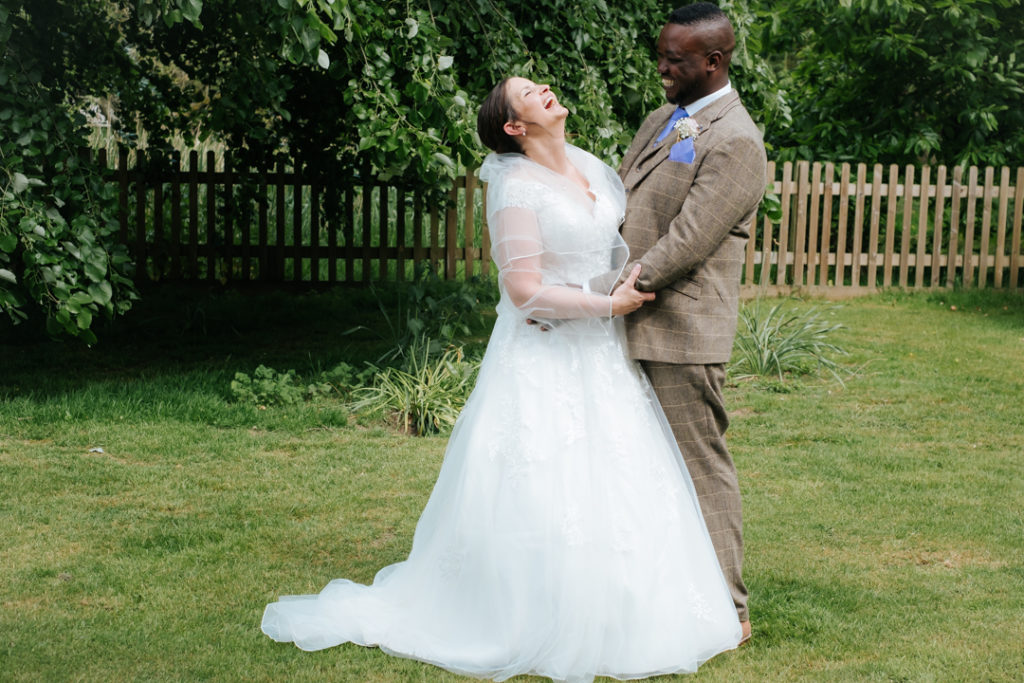 bride and groom laugh together as they embrace after their outdoor wedding ceremony at Worton Hall wedding venue