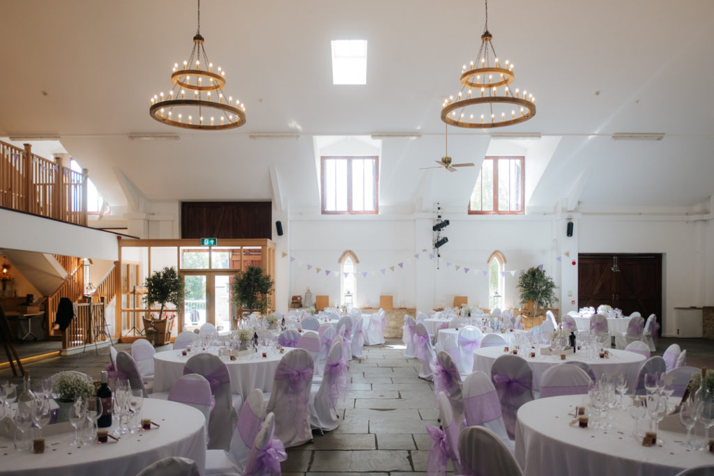 the main hall at Worton Hall dressed and ready for an African Fusion wedding reception. Purple bows are wrapped around the chairs.