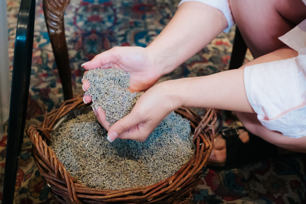 brides hands lifting fresh lavendar confetti out of a basket at Worton Hall wedding venue