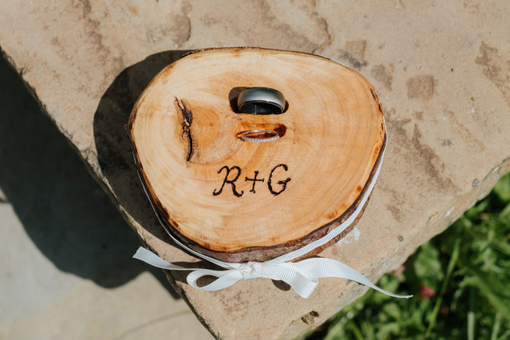 wedding rings held in a piece of cut wood engraved with the bride and groom's initials "R & G" for their Worton Hall wedding