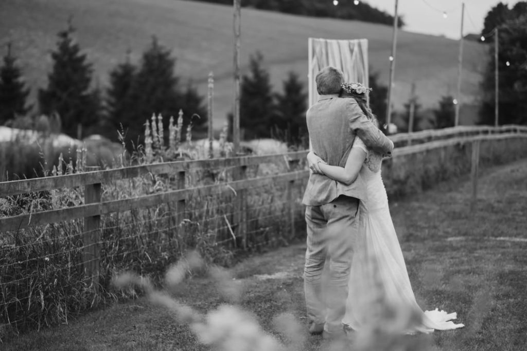 bride and groom embrace and look out to the lake outside the tipi at Hadsham Farm on thier fun, relaxed festival wedding day. such a please for Charlie Flounders to photograph
