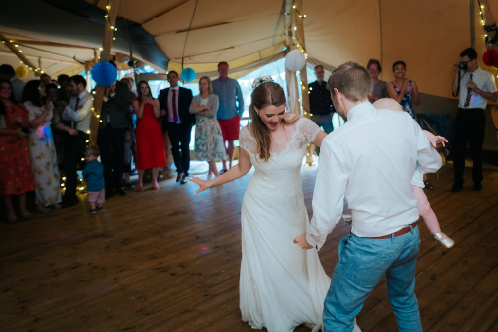 bride and groom perform their first dance inside the tipi at Hadsham Farm weddings, Banbury as their guests look on. Such a fun wedding to photograph