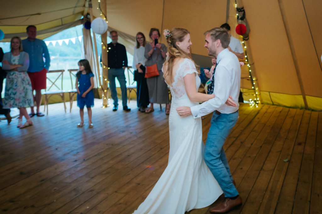 bride and groom perform their first dance inside the tipi at Hadsham Farm weddings, Banbury as their guests look on. Such a fun wedding to photograph