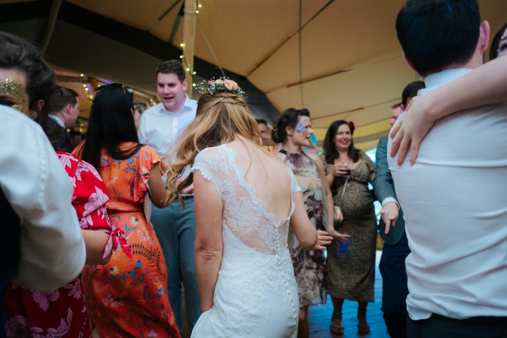Bride dancing with all of her friends on the dancefloor inside her Tipi wedding at Hadsham farm.