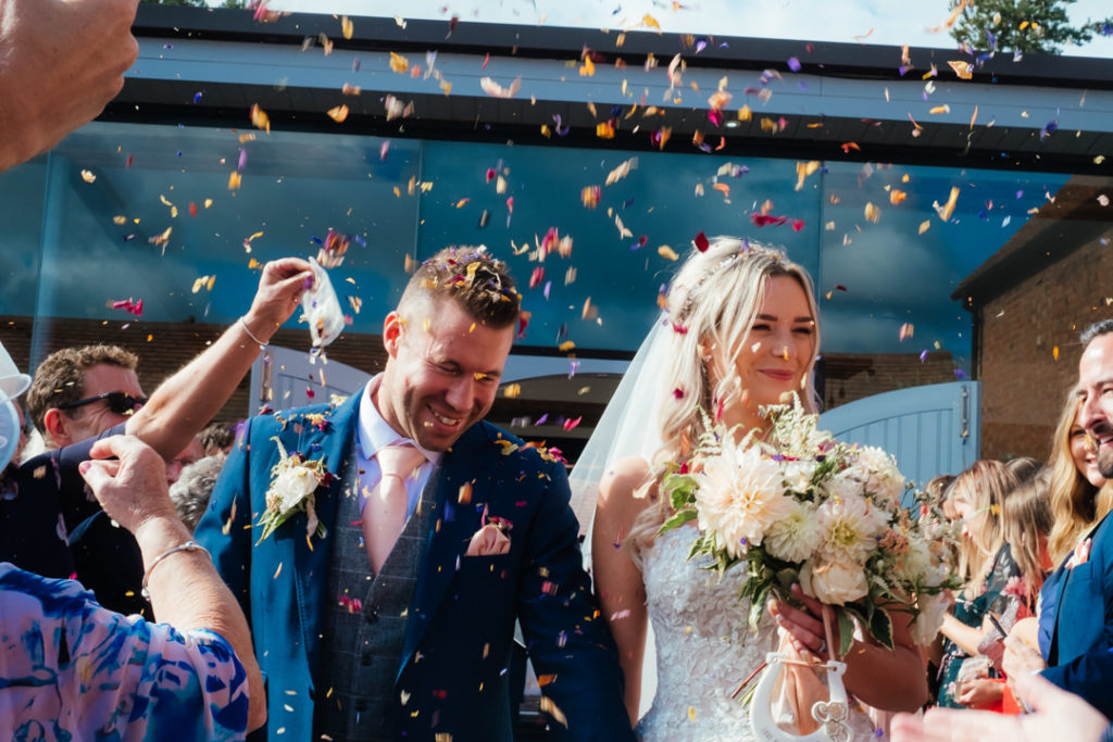 wedding photo of bride and groom walking through confetat swallows nest wedding barn 