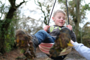 Young boy on woodland rope swing