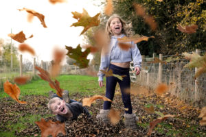 Children rolling and playing in autumn leaves
