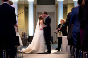 A bride and groom kissing at the end of their wedding ceremony in the Ashmolean Museum Oxford