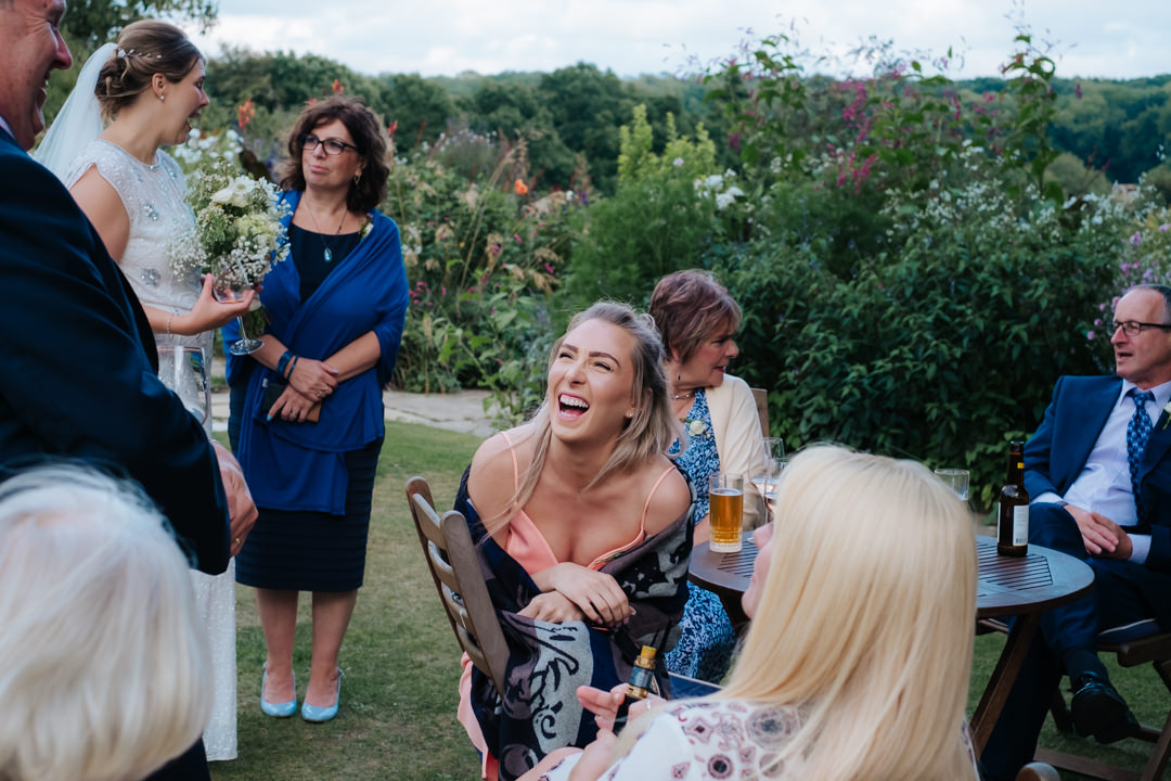 Wedding guests laughing at wedding reception at Gravetye Manor