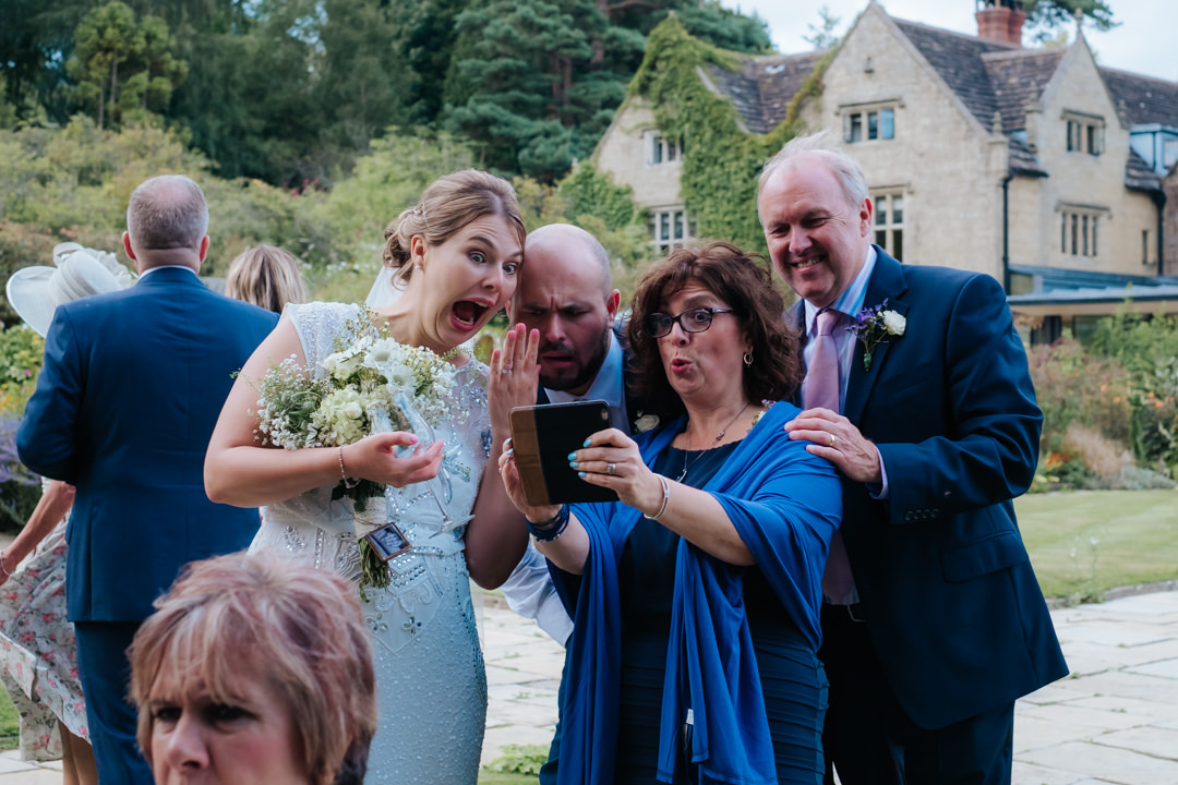 Fun bride and guests take selfie at their wedding reception at Gravetye Manor