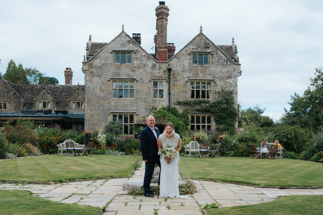 Bride and her father laughing outside the stunning house of Gravetye Manor before she goes to her wedding at Nymans Gardens